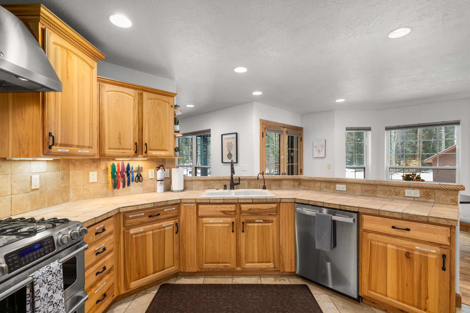 A modern kitchen with wooden cabinets, a stainless steel stove, and a dishwasher.