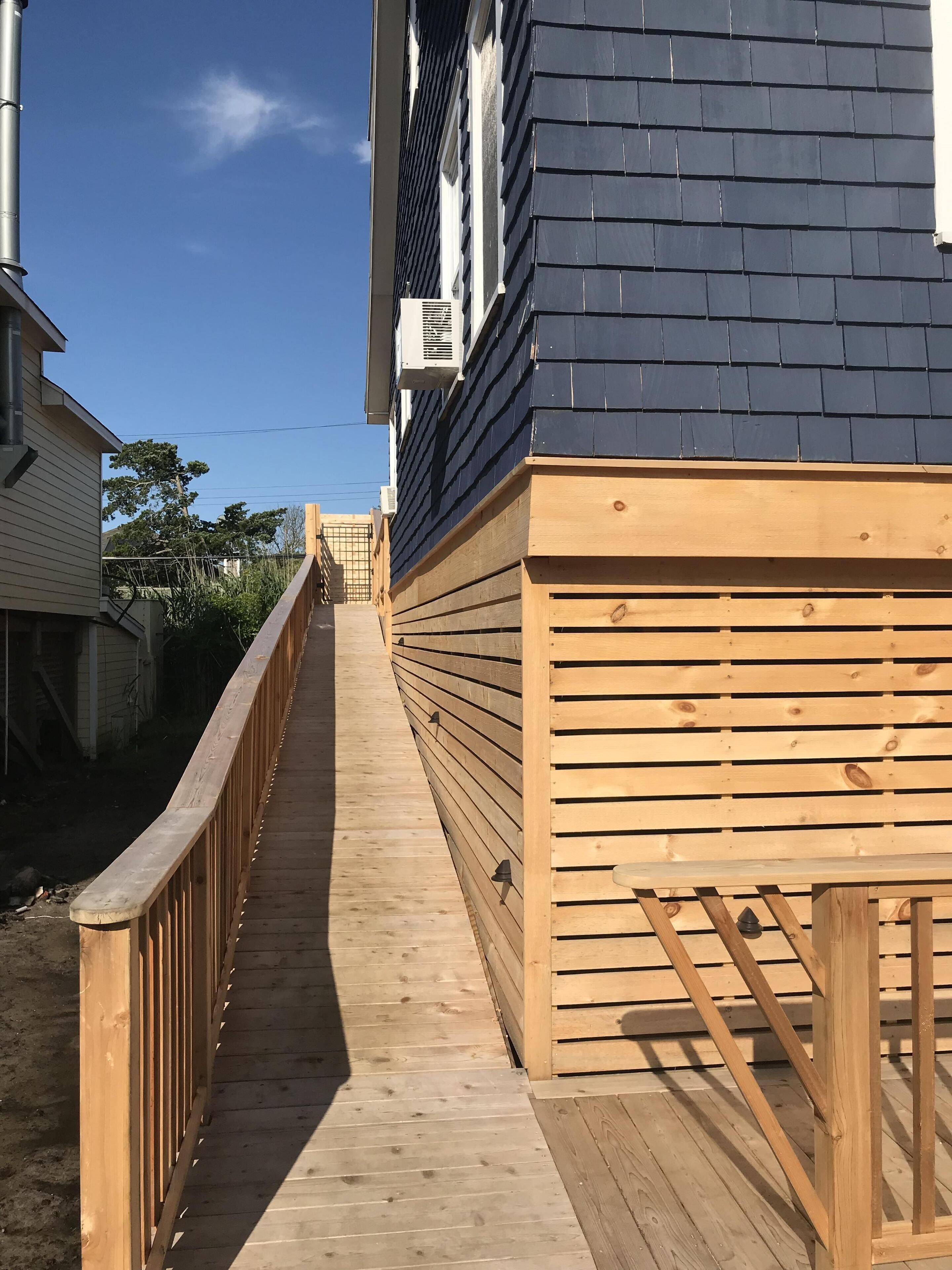 Una terraza de madera que conduce a una casa con tejado de tejas oscuras.