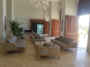 A spacious lobby with a piano, sofas, and a large plant.