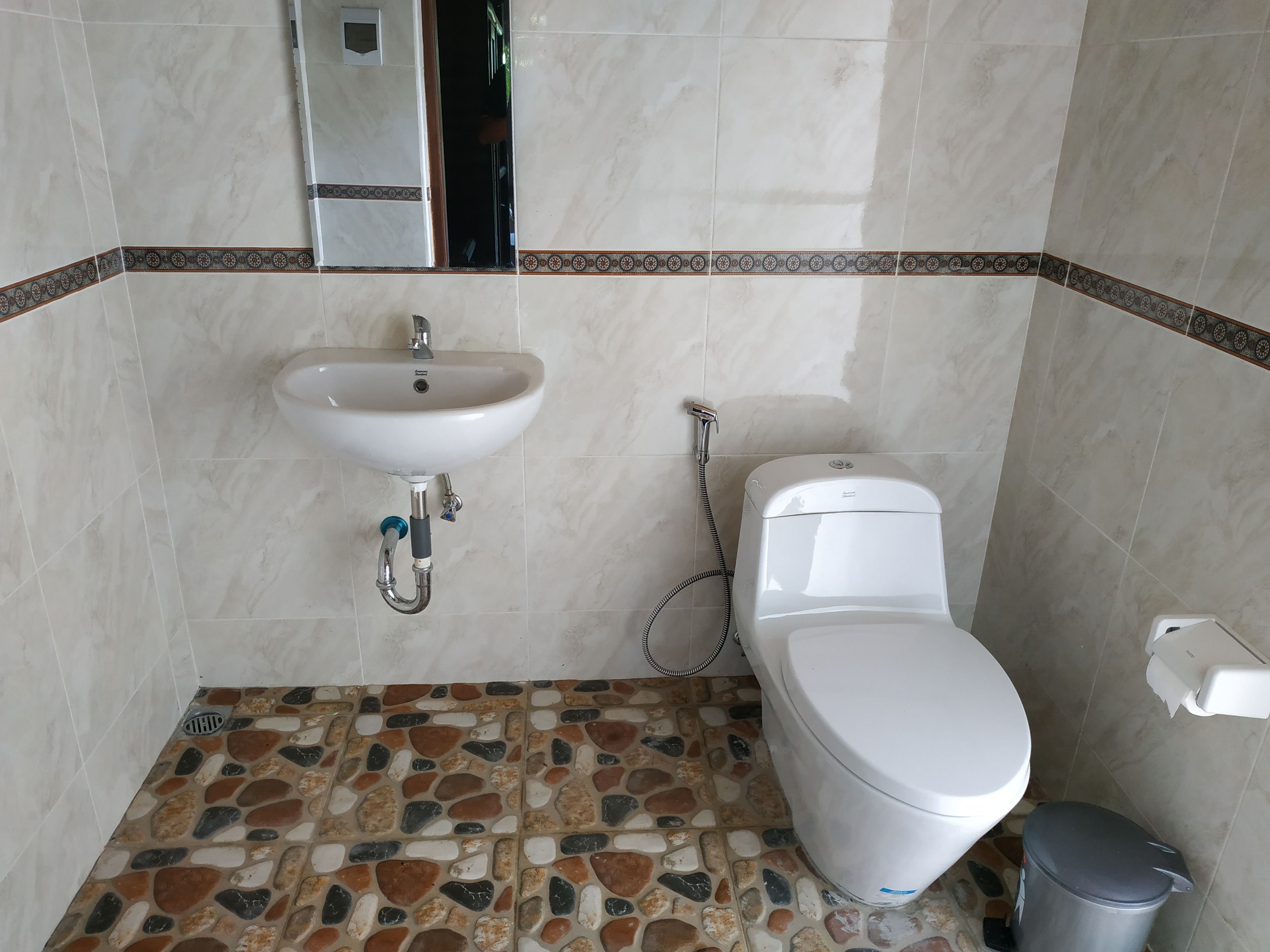 A bathroom with a white sink, toilet, and shower. The floor has a mosaic tile pattern.
