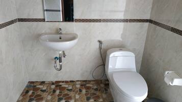 A bathroom with a white sink, toilet, and shower. The floor has a mosaic tile pattern.