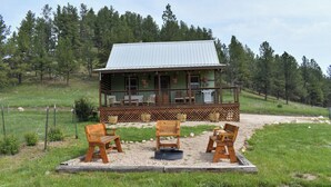 A rustic cabin with a porch, outdoor seating, and a gravel area. - Black Hills Farmhouse (Custer)