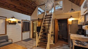 A loft-style room with a wooden staircase, a kitchen area, and a seating area with a table and chairs. - Black Hills Farmhouse (Custer)