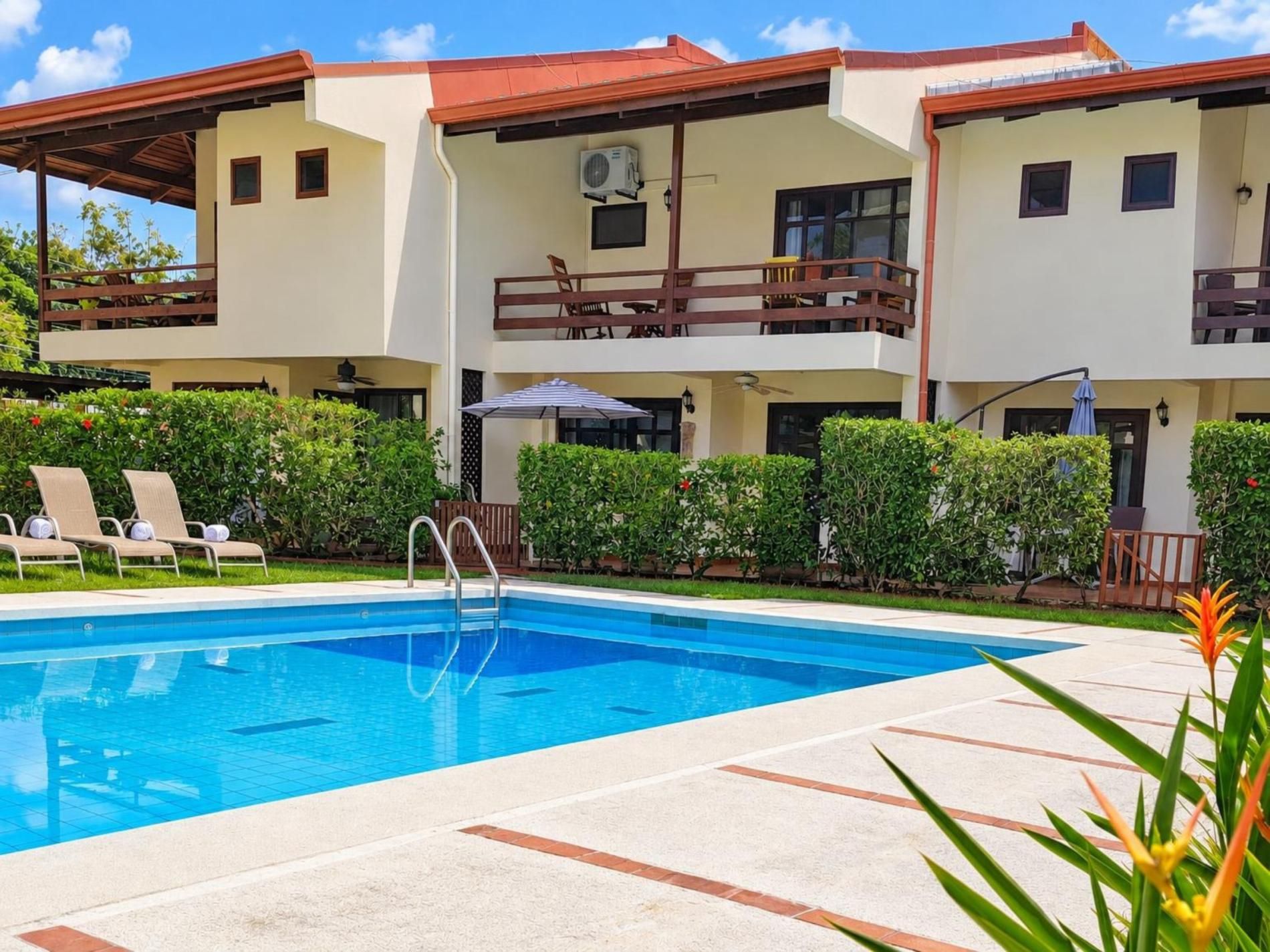 A two-story building with a swimming pool, outdoor seating, and a covered patio area.