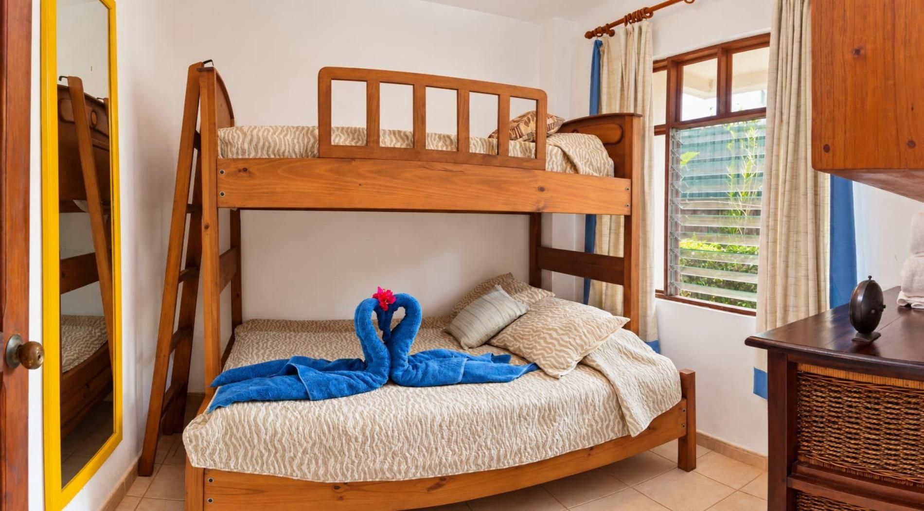 A bunk bed with a wooden headboard, a blue towel, and a decorative swan.