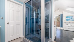 A modern interior with a glass door leading to a storage area, a white door, and a view of a room with a large window.