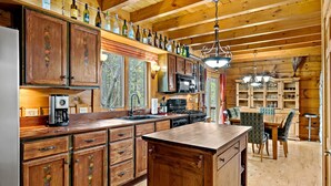 Eine Holzhütte mit einer Kücheninsel, Holzschränken, einer Kaffeemaschine und einem Essbereich mit Tisch und Stühlen.