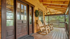 Eine Holzhütte mit Veranda, einem Schaukelstuhl und einer Tür mit zahlreichen Fenstern.