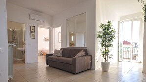 A spacious living area with a sofa, a potted plant, and a large mirror.