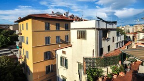 A multi-story building with balconies, a rooftop terrace with potted plants, and a clear blue sky.