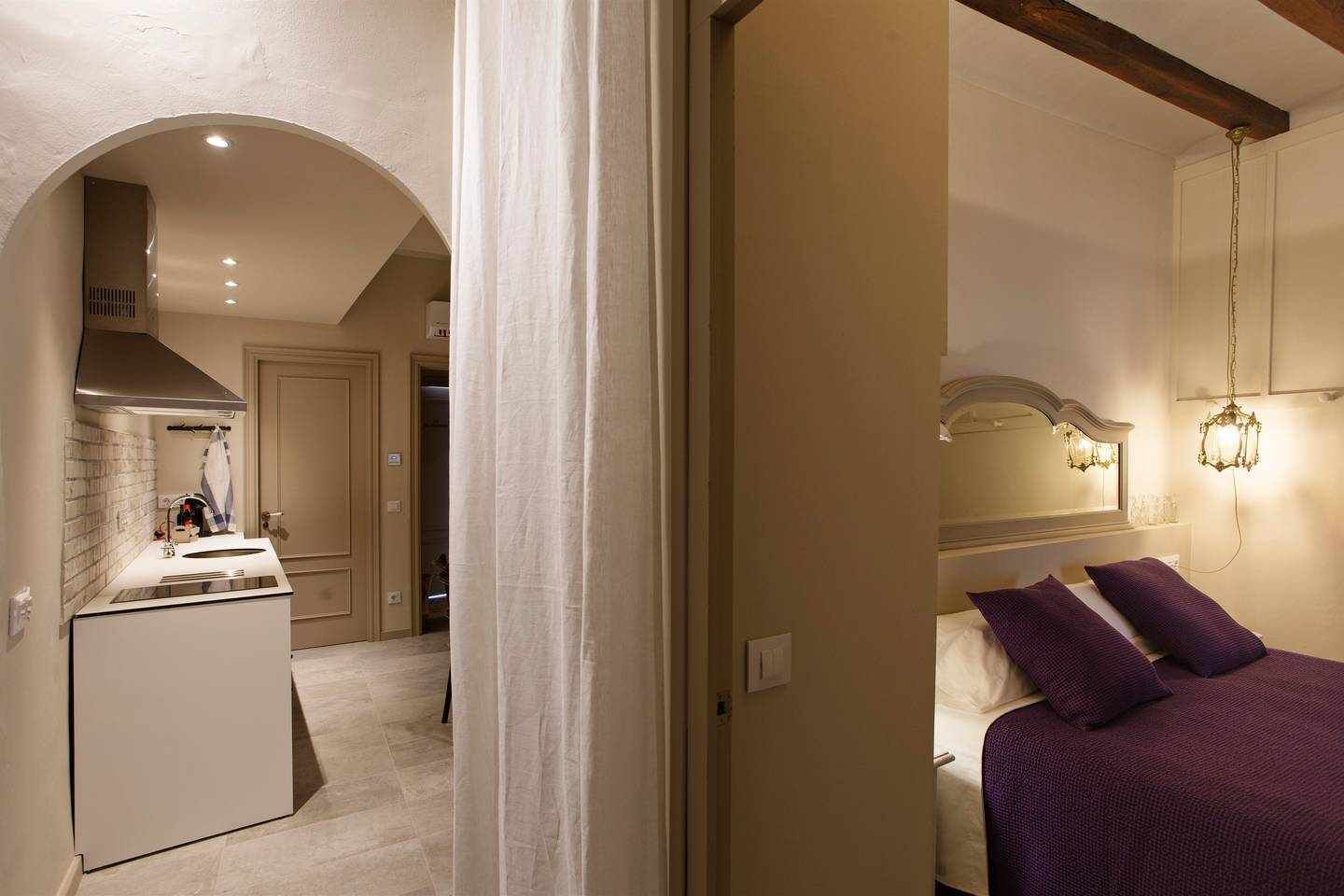 Une chambre d’hôtel comprenant un lit, une salle de bain avec un lavabo et un miroir, et un coin cuisine.