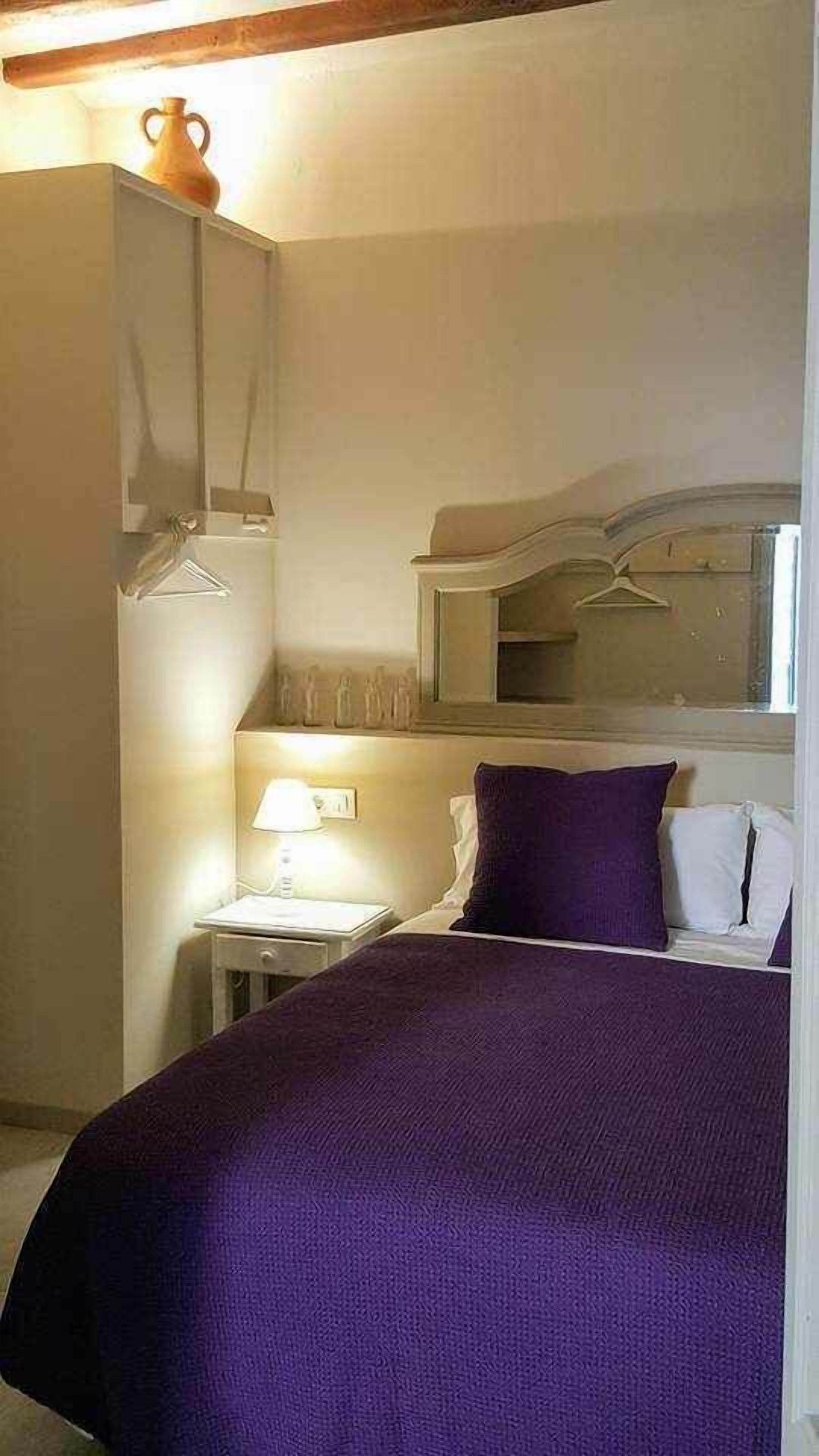 Ein Schlafzimmer mit einem Bett, einem Nachttisch, einer Lampe, einem Spiegel und einem Kleiderschrank.