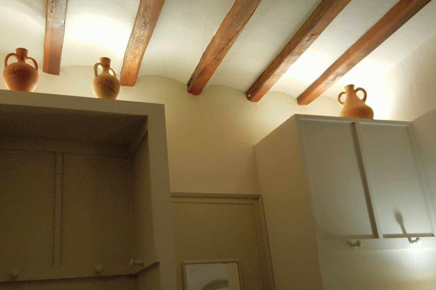 Une pièce avec des poutres apparentes, une armoire blanche et une porte blanche.