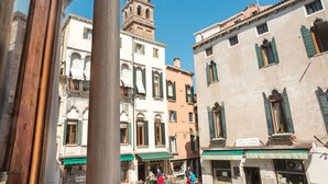 Una calle estrecha con edificios históricos, incluyendo un campanario y un cartel que dice "Campo S. Maria Water Down".