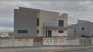 A modern two-story residential building with a flat roof, a balcony on the upper floor, and a gated entrance. - Mikaela Guest House (Odivelas)