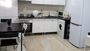 A modern kitchen with white cabinets, a black countertop, a sink, a stove, a microwave, a refrigerator, and a washing machine. - Mikaela Guest House (Odivelas)