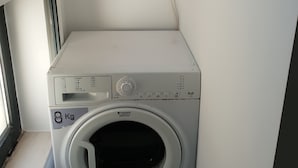 A compact, white washing machine with a front-loading door, a control panel, and a label indicating it can handle 8 kg of laundry. - Mikaela Guest House (Odivelas)