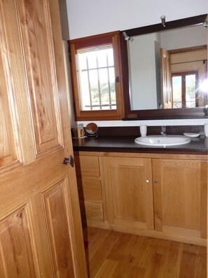 Une salle de bain en bois avec un grand miroir, un lavabo et des armoires.