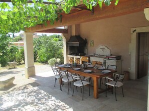 An outdoor dining area with a wooden table and chairs, a grill, and a view of the surrounding greenery. - Vacation rental SAINT REMY DE PROVENCE LS1-196 (Saint Remy de Provence)