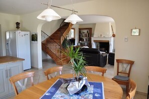 A dining area with a wooden table, chairs, and a potted plant. A staircase leads to another room. - Vacation rental SAINT REMY DE PROVENCE LS1-196 (Saint Remy de Provence)