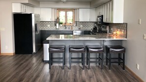 Una cocina moderna con una isla central, taburetes de bar y un refrigerador negro.