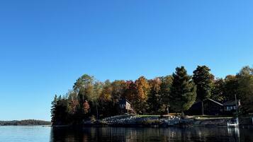 A calm lake with a wooden dock and a house surrounded by trees.