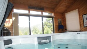 Een hottub bij een houten chalet, met een bordje ‘Welkom bij de Lodge’ boven de ingang.
