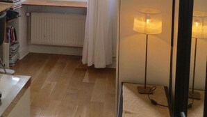 A room with a window, a radiator, a mirror, and a lamp. - Charming studio in the Marais (Paris)