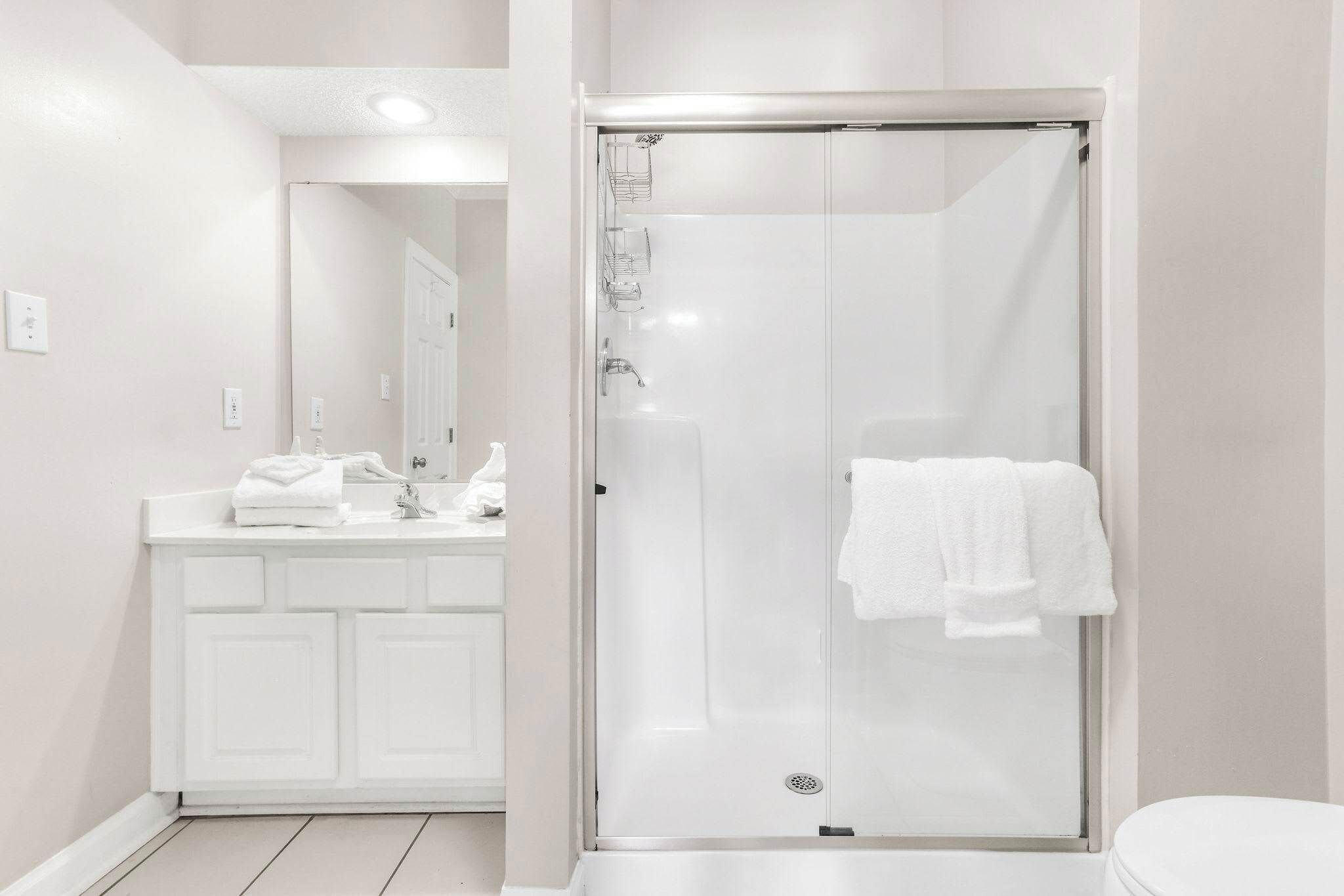 A modern bathroom with a glass-enclosed shower, a white vanity with a mirror, and a toilet.