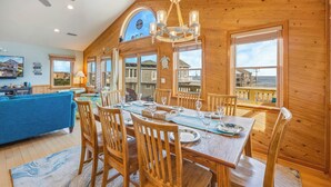 A wooden dining area with a table set for six, surrounded by wooden chairs.