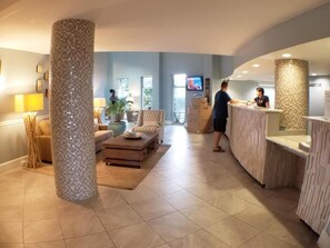 A hotel lobby with a reception desk, seating area, and a large pillar.
