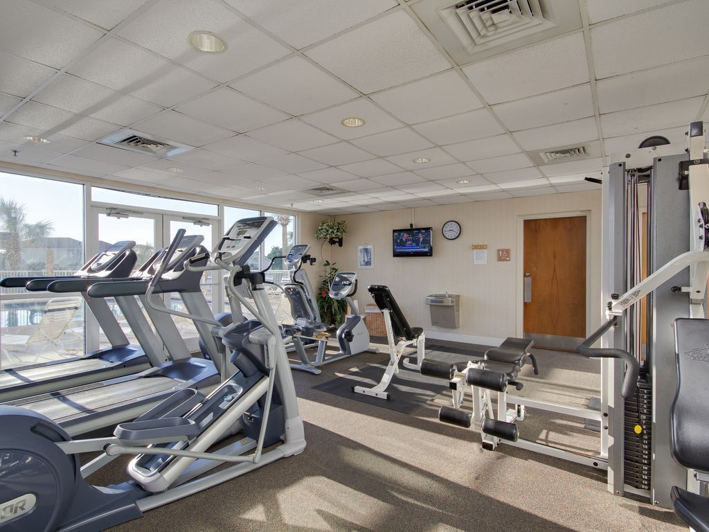 A gym with treadmills, weight machines, and a television on the wall.