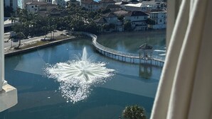 Une vue d’un quartier résidentiel avec une fontaine centrale, un pont et un ciel bleu dégagé.