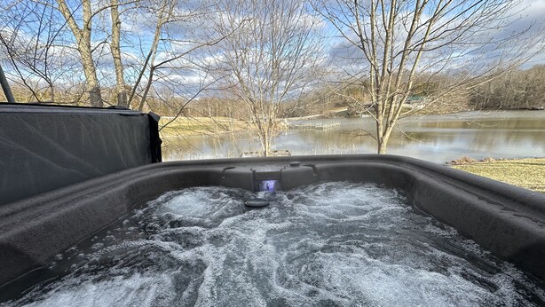A hot tub with a control panel, surrounded by a natural landscape with trees and a body of water. - KY BOURBON TRAIL LAKEFRONT HOUSE WITH DOCK SLEEPS 8! Year round Hot tub! (Lawrenceburg)