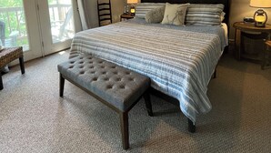 A bedroom with a large bed, a ceiling fan, a bench, and a view through a glass door. - KY BOURBON TRAIL LAKEFRONT HOUSE WITH DOCK SLEEPS 8! Year round Hot tub! (Lawrenceburg)