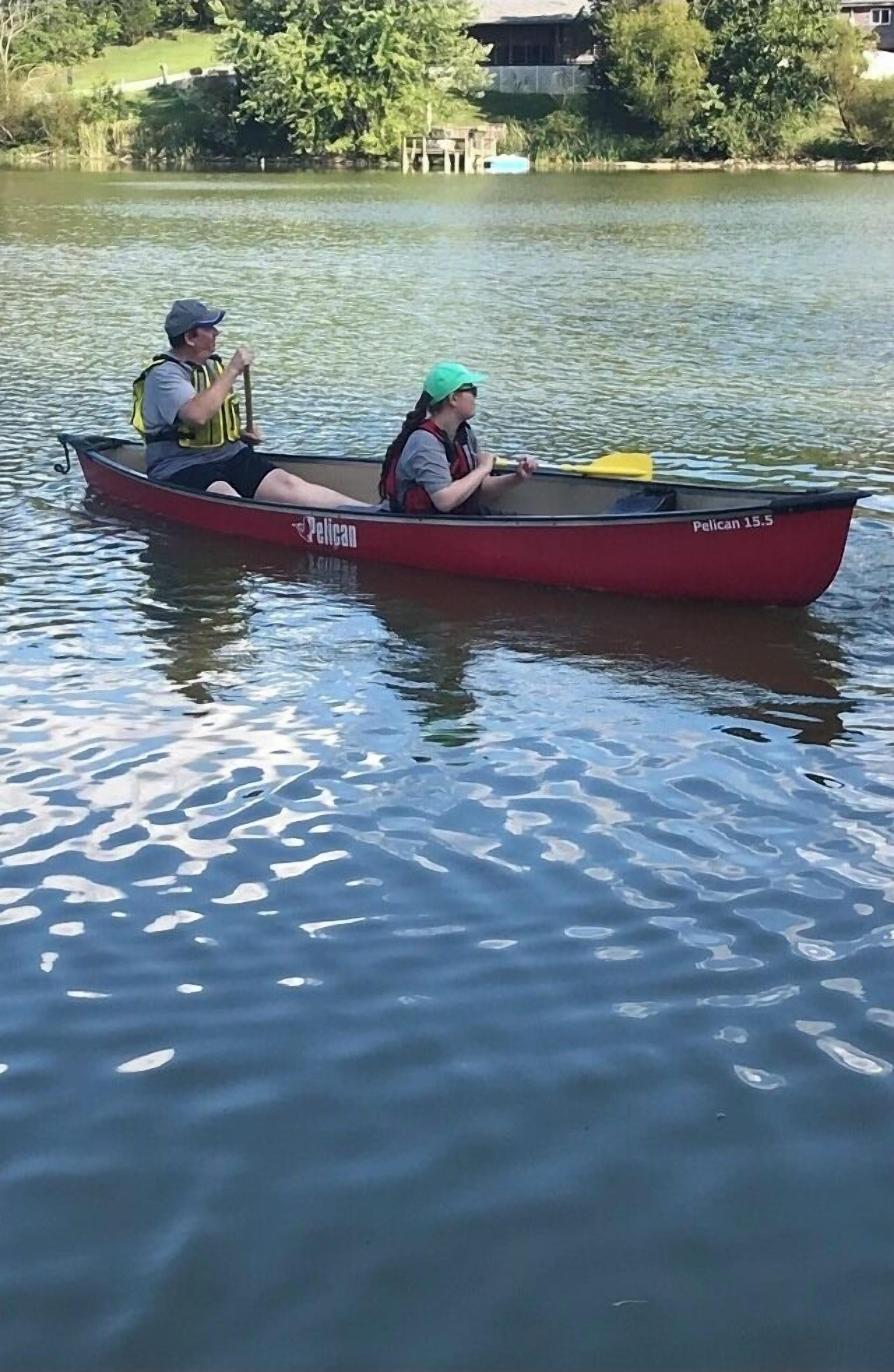 A red Pelican 15.5 boat on calm water.