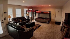 A living room with a sofa, a bunk bed, a television, and a door.