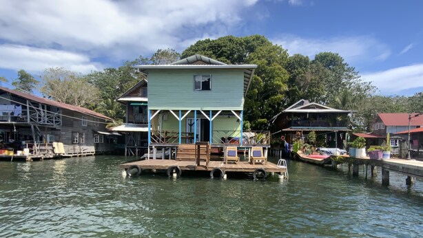Ein schwimmendes Haus mit einer Anlegestelle, umgeben von Wasser und Bäumen.