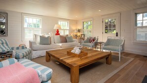 Una sala de estar acogedora con una mesa de centro de madera, sofás blancos y sillones estampados.