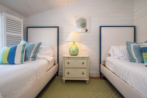 A room with two beds, a nightstand with a lamp, and a wall-mounted artwork.