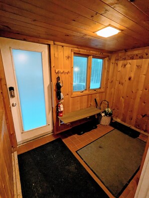 A wooden interior with a bench, a fire extinguisher, and a window.