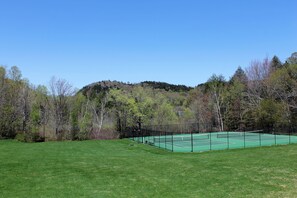A tennis court surrounded by a forested area with a clear sky. - Spacious Sugarbush Retreat - Wood Stove, Outdoor Pool, Minutes to Sugarbush (Warren)