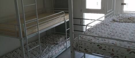 Un dormitorio con literas, una ventana y una puerta.