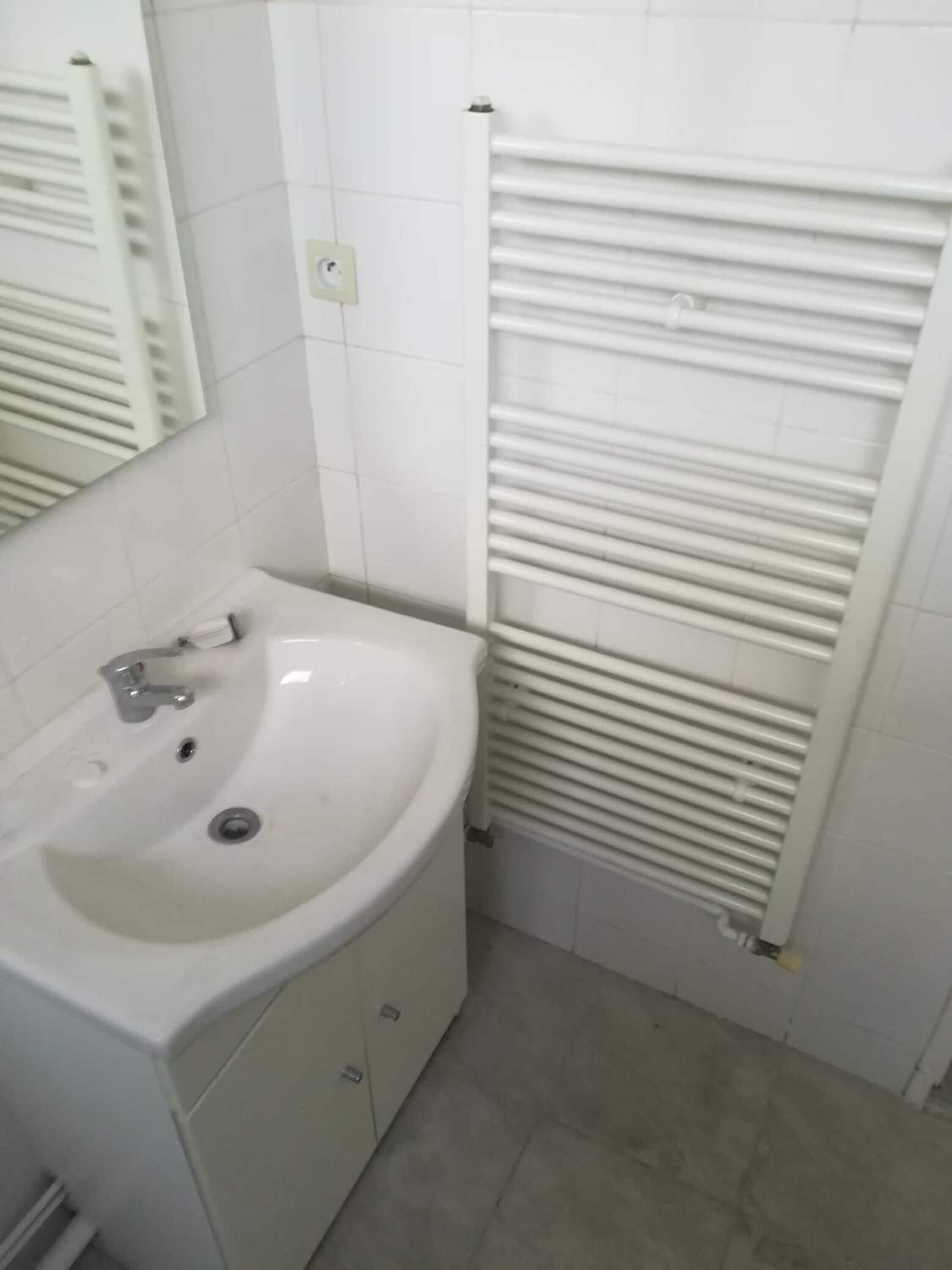 A bathroom with a white sink, mirror, and radiator.