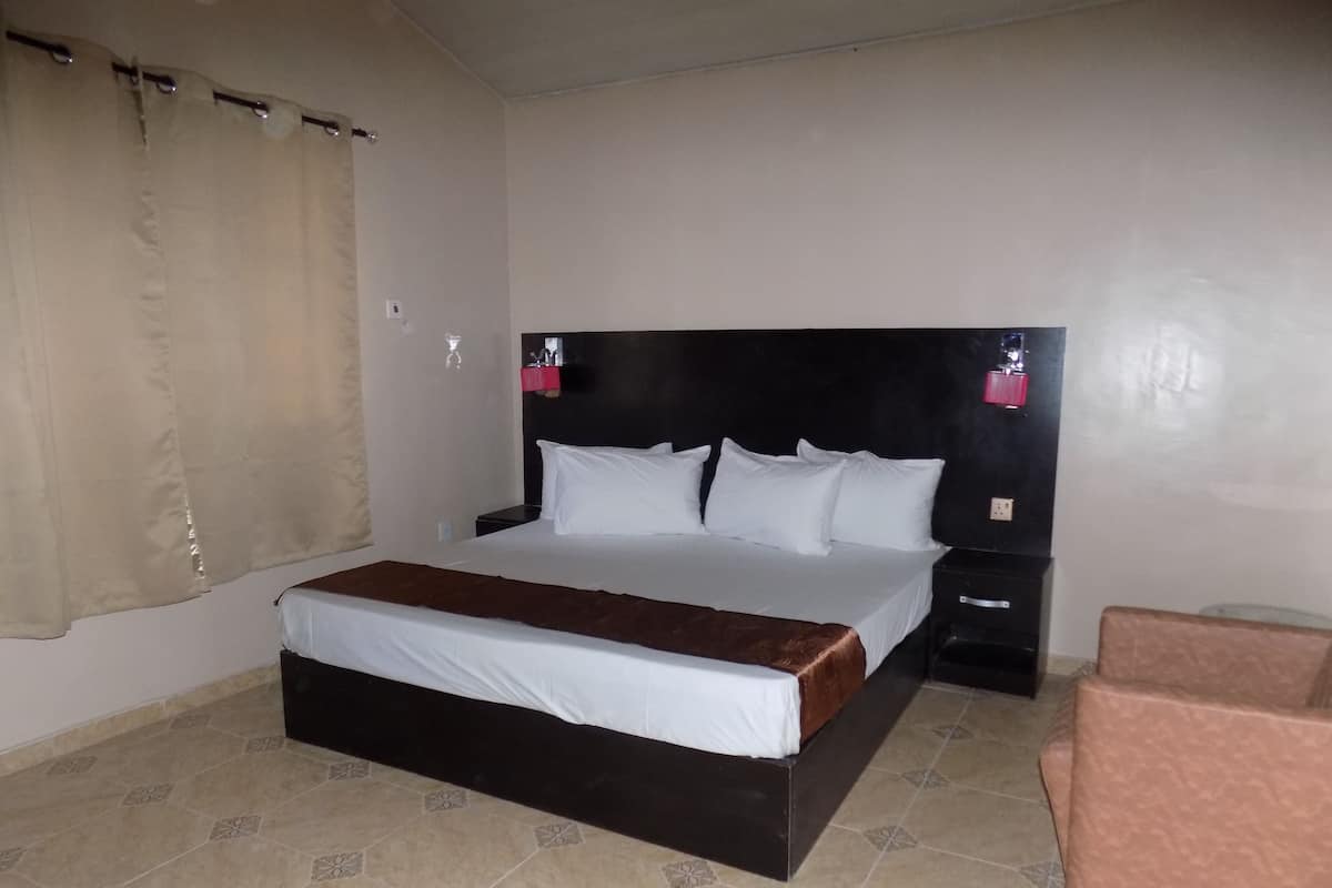 Une chambre d’hôtel avec un grand lit, une table de chevet, une chaise et un rideau.