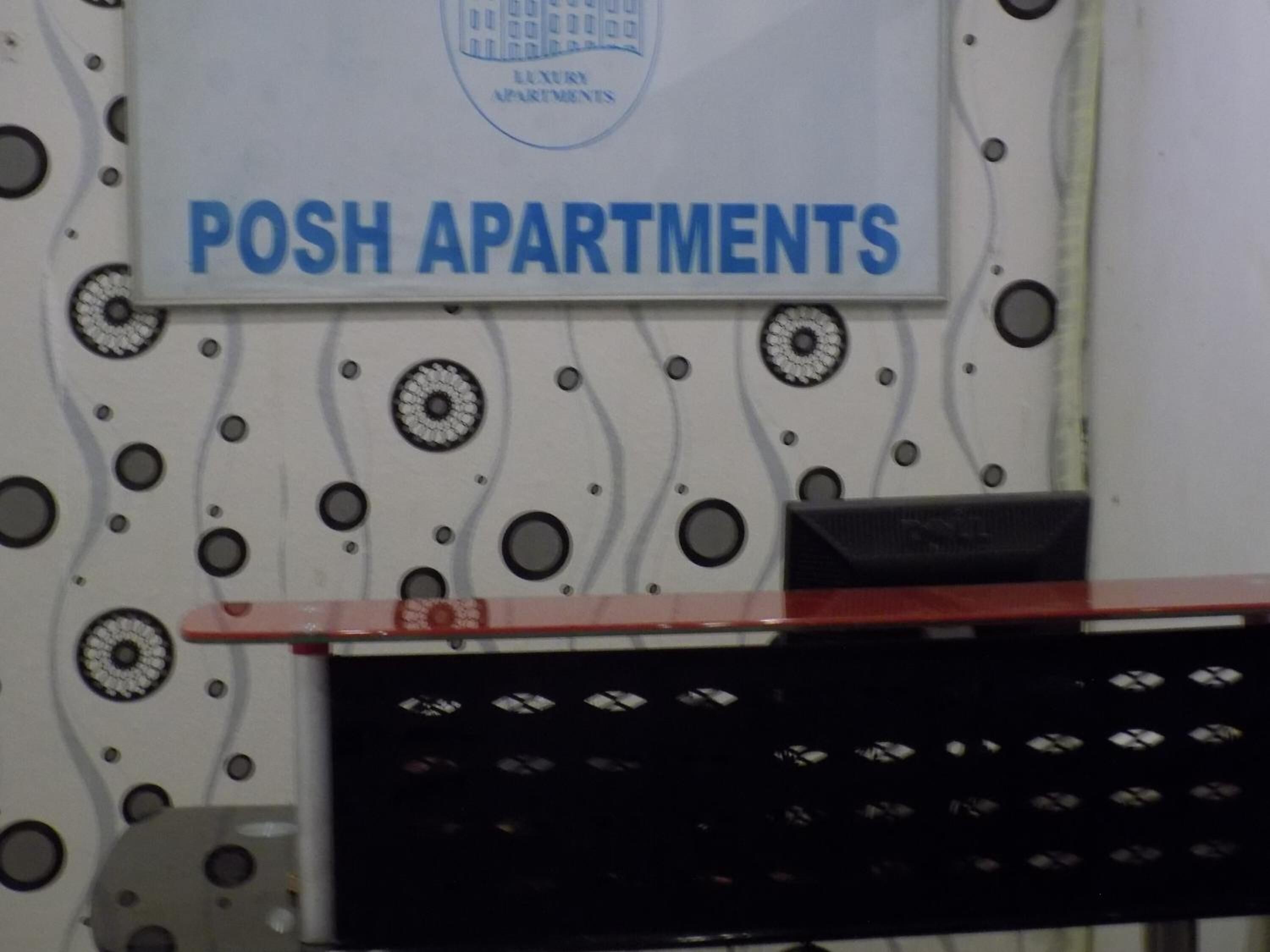A sign for 'POSH APARTMENTS' with a decorative wall featuring circular patterns.