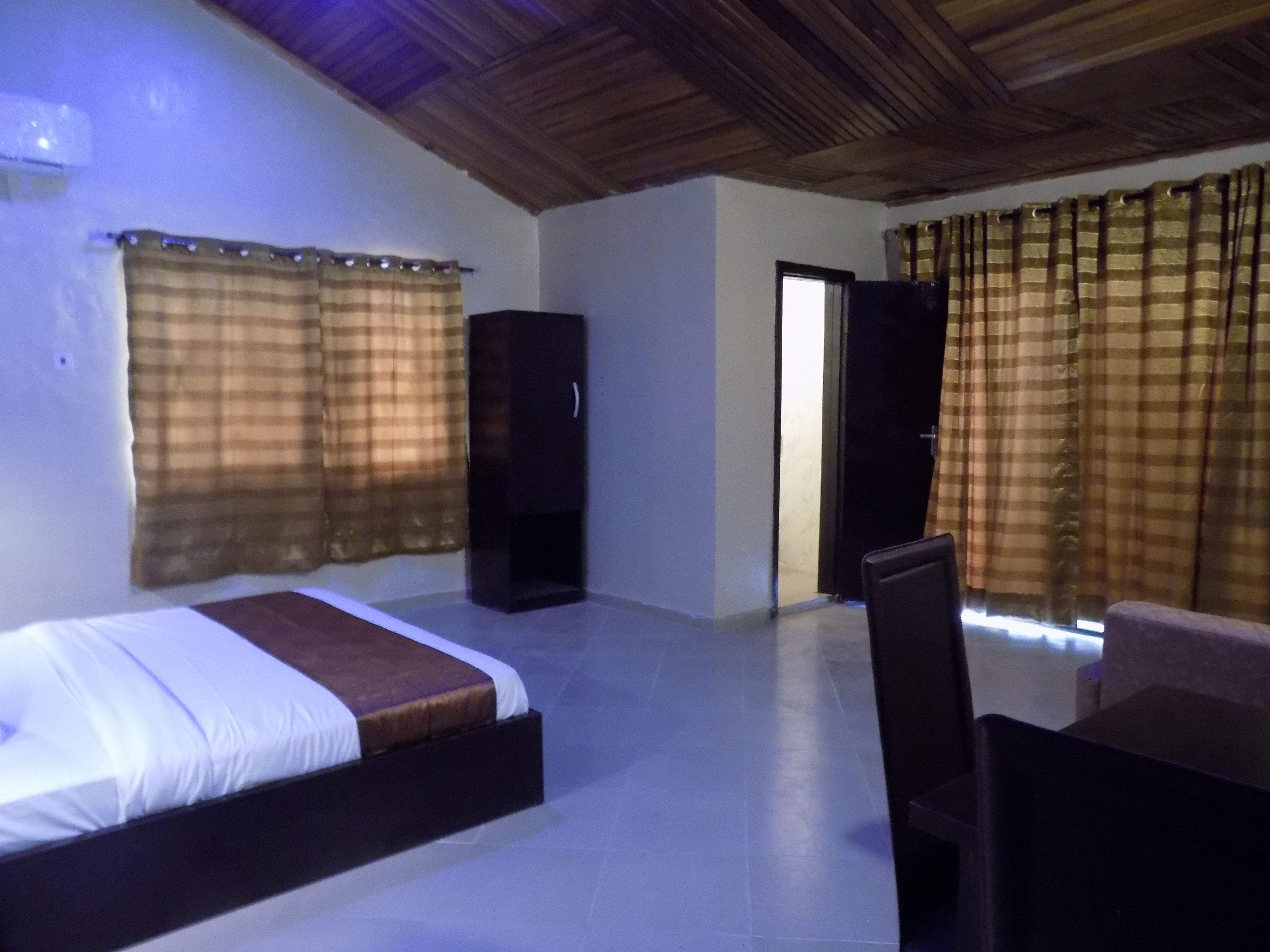 A room with a bed, a wardrobe, a door, and curtains.