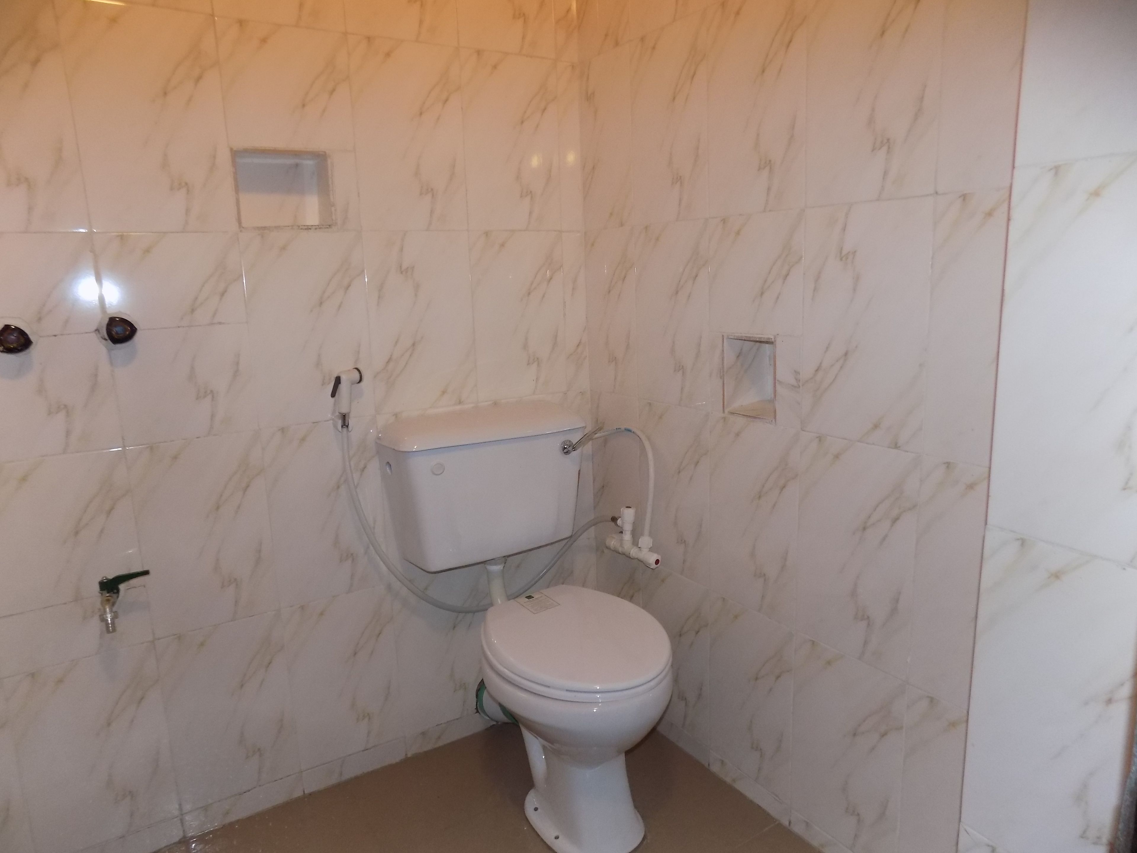A bathroom with a toilet, a wall-mounted sink, and a shower area.