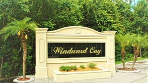 Un cartello con la scritta 'Windward Cay', circondato da palme e vegetazione.