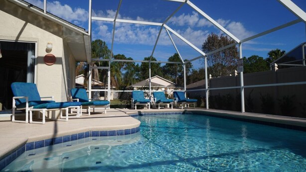 Una piscina con sedie blu e una zona coperta.